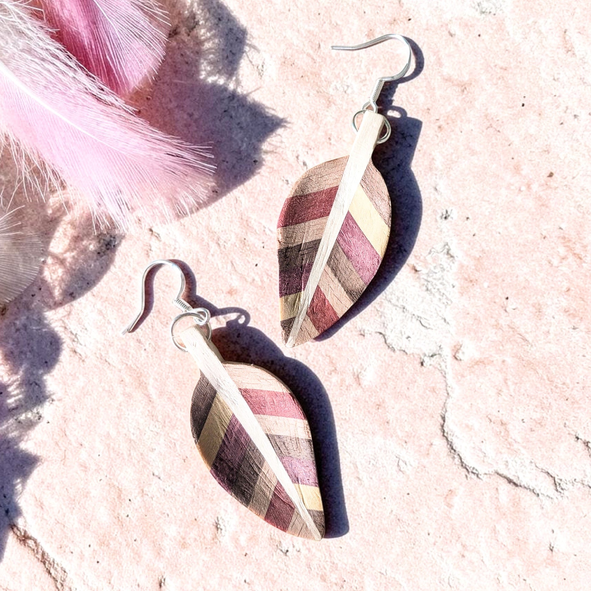 A pair of Handcarved Wooden leaf earrings, the woods are English holly, yellowheart, purpleheart, pink ivory wood and walnut in a beautiful striped design, they are finished with sterling silver hooks and are extremely lightweight 